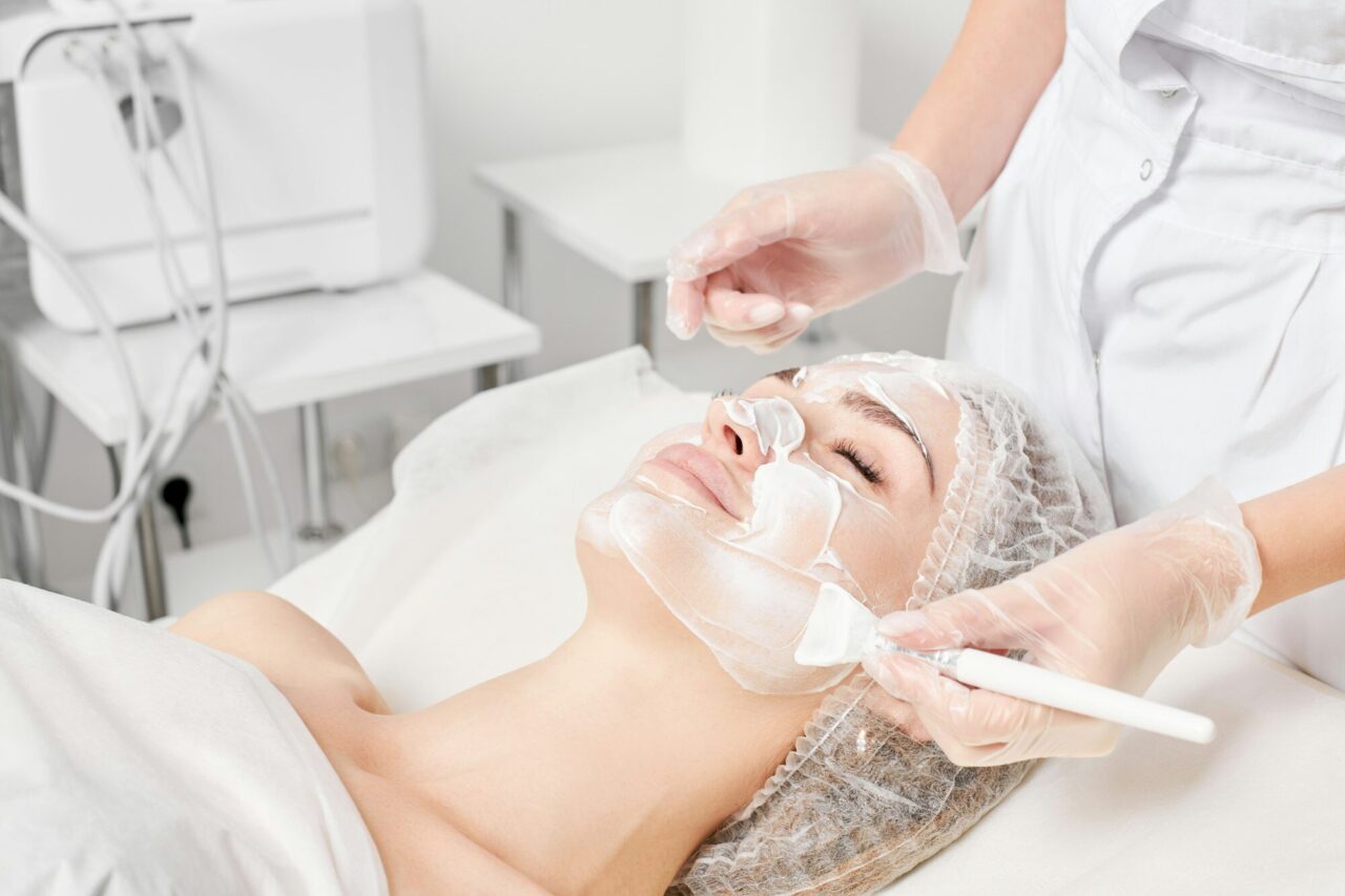 Estetista applica una maschera crema sul viso per il ringiovanimento della pelle